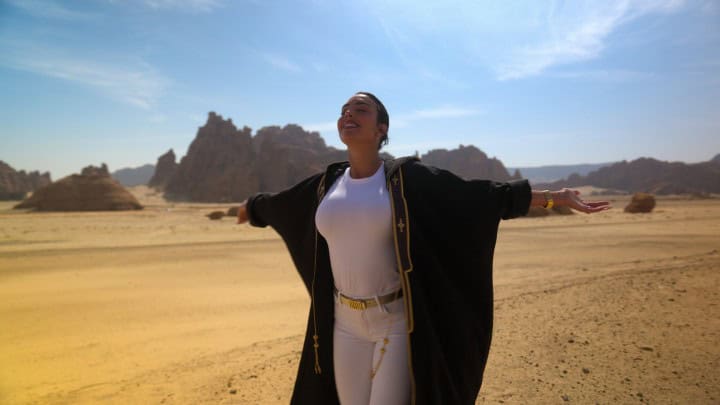 امرأة تقف في صحراء تحت السماء الزرقاء